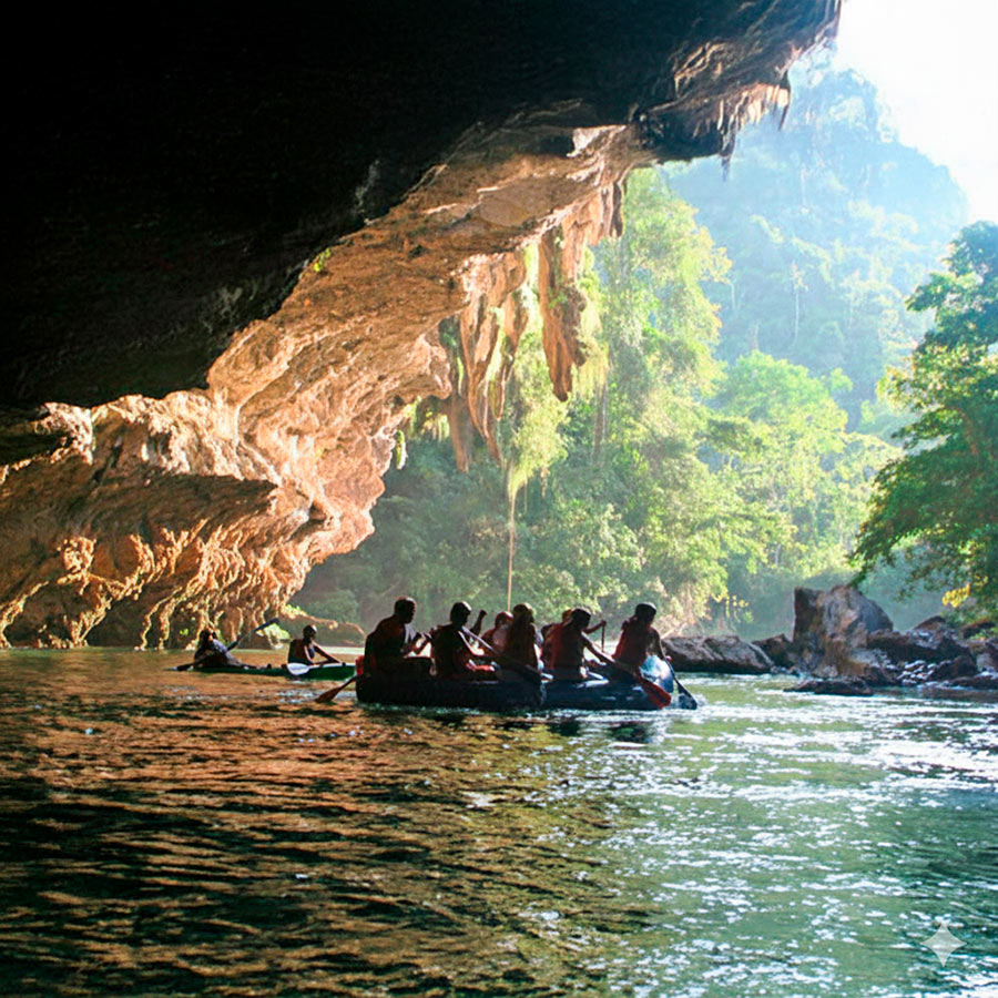 Grupo de turistas realizando rafting o body rafting saliendo de una imponente cueva de mármol en Río Claro.