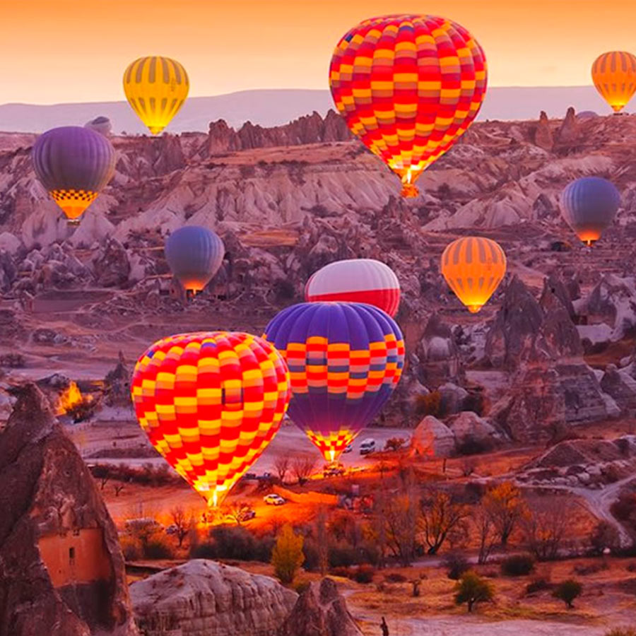 Globos aeroestáticos al amanecer en la región de Capadocia, Turquía. Formaciones rocosas conocidas como "chimeneas de hadas". Reserva en Viajes Comfama